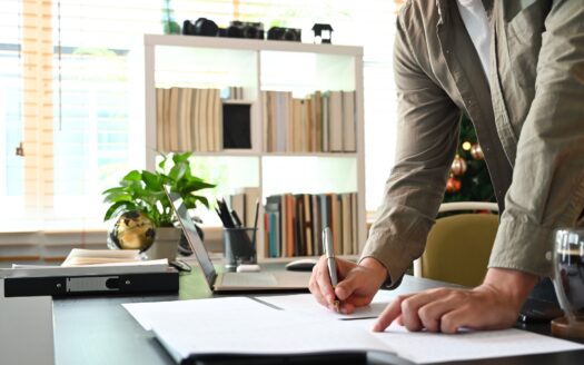 Cropped shot young man standing in home office and writing information on document.